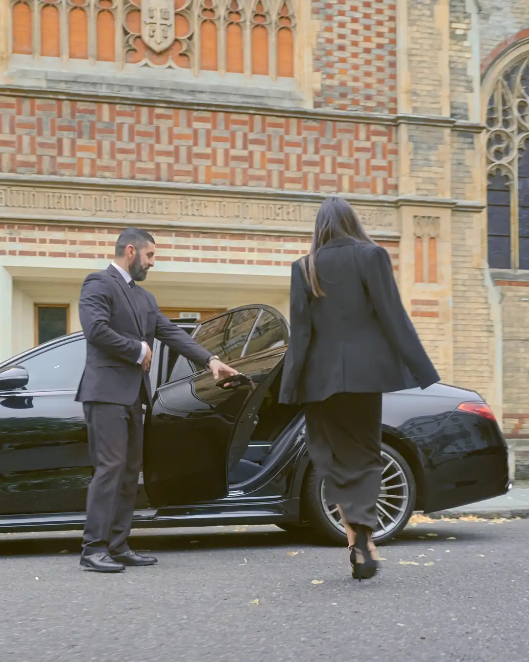 Chauffeur assisting a female executive into a luxury Mercedes-Benz in London, highlighting professional executive security service.