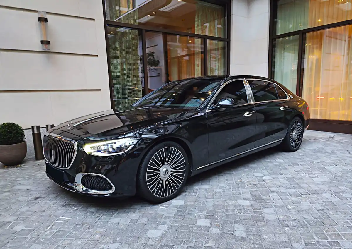 A luxurious black Mercedes-Maybach S-Class parked outside a modern building, highlighting the premium specifications of the chauffeur fleet.